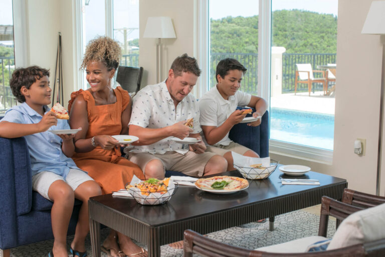 Family sharing a meal in The Hills St. John clubhouse with pool and ocean views