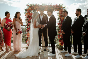A couple getting married in front of a rose arch at one of The Hills St. John villas overlooking Cruz Bay.