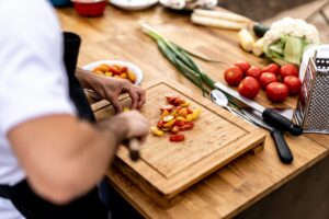 A private chef slicing grape tomatoes on a wooden cutting board in preparation for a private event.