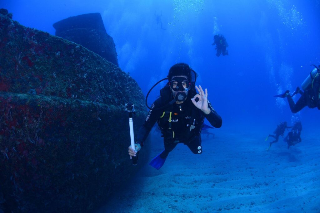 A scuba diver giving the "OK" signal while exploring an underwater shipwreck.